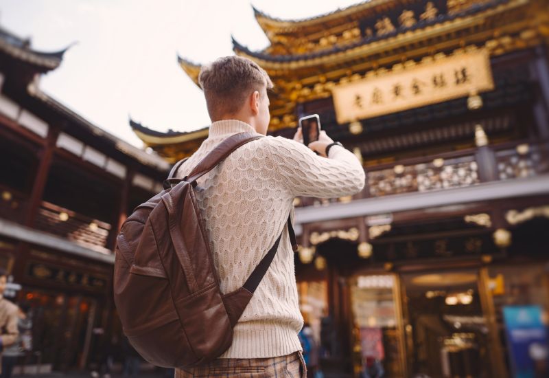 male tourist taking photos of a pagoda at Yuyuan market in Shanghai during his visit to China