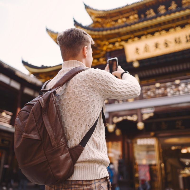 male tourist taking photos of a pagoda at Yuyuan market in Shanghai during his visit to China